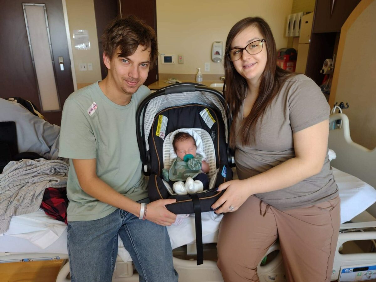 New parents pose with newborn son in hospital