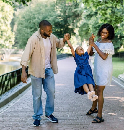 Parents play with daughter during walk in the park